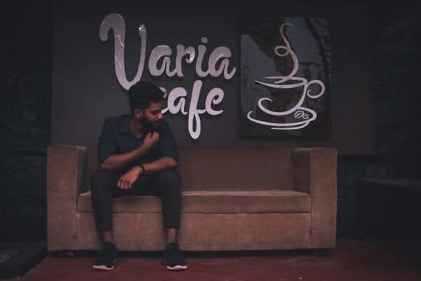 A man sits in front of a Varia café sign 