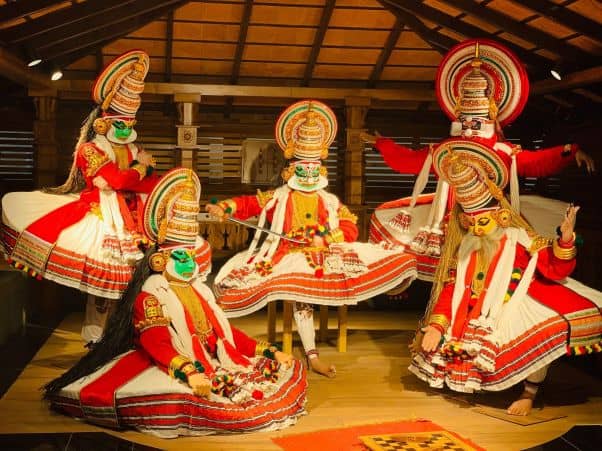 Five masked actors perform Kathakali on a stage that looks like a house