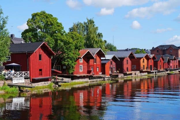 A row of red, wooden houses sits beside the water in Porvoo, Finland.