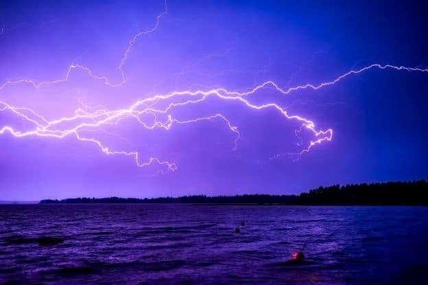 At dusk, lighting flashes through a purple-colored sky above a body of water in Finland.