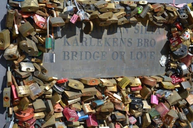 Dozens of padlocks adorn Helsinki's "Bridge of Love." This close-up image shows the plaque identifying the bridge.