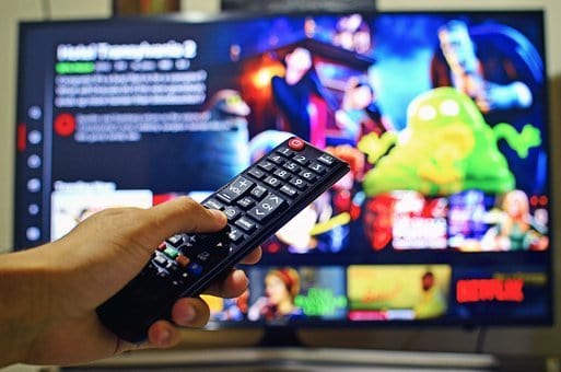 A person holding a remote control looks at a variety of choices on a streaming service, such as Netflix.