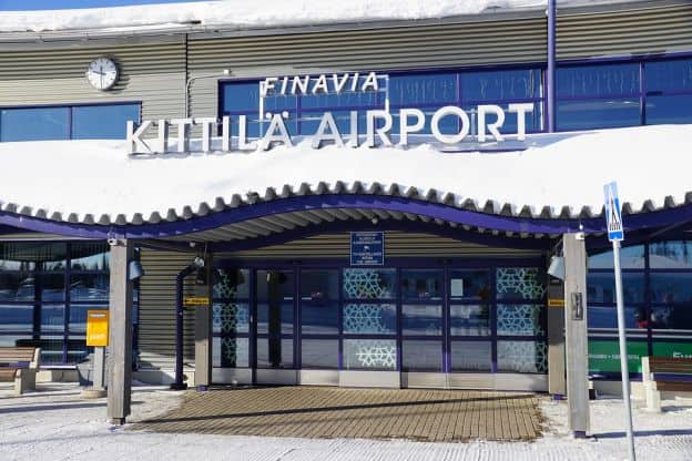 An entrance to Kittilä Airport in Finland, with snow on the roof and sidewalk of the building.