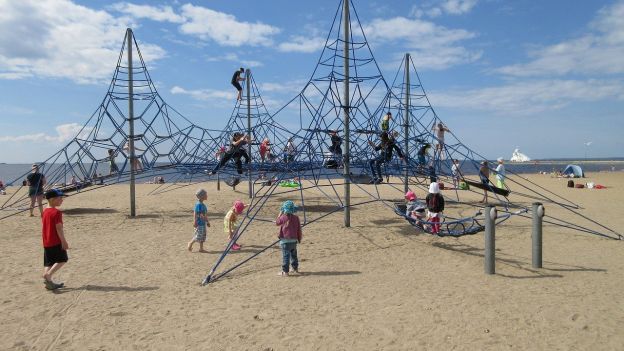 Several children play on an outdoor "jungle gym" on the beach in Oulu.