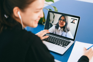 A language tutor and student speak on a video call through a laptop screen.